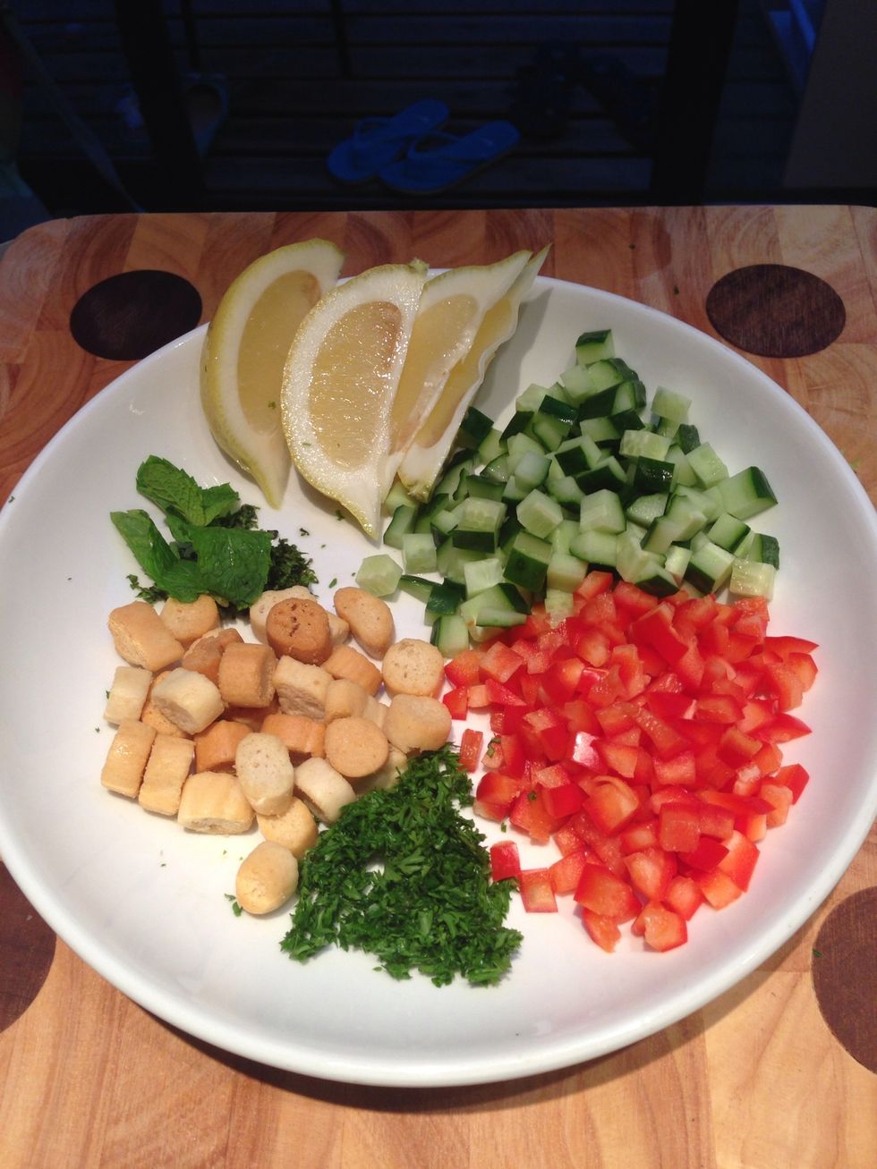 Meanwhile, chop the parsley & mint. Cut the cucumber, pepper in small cubes & wedge the lemon. Prepare the croutons and set aside for garnishing later.