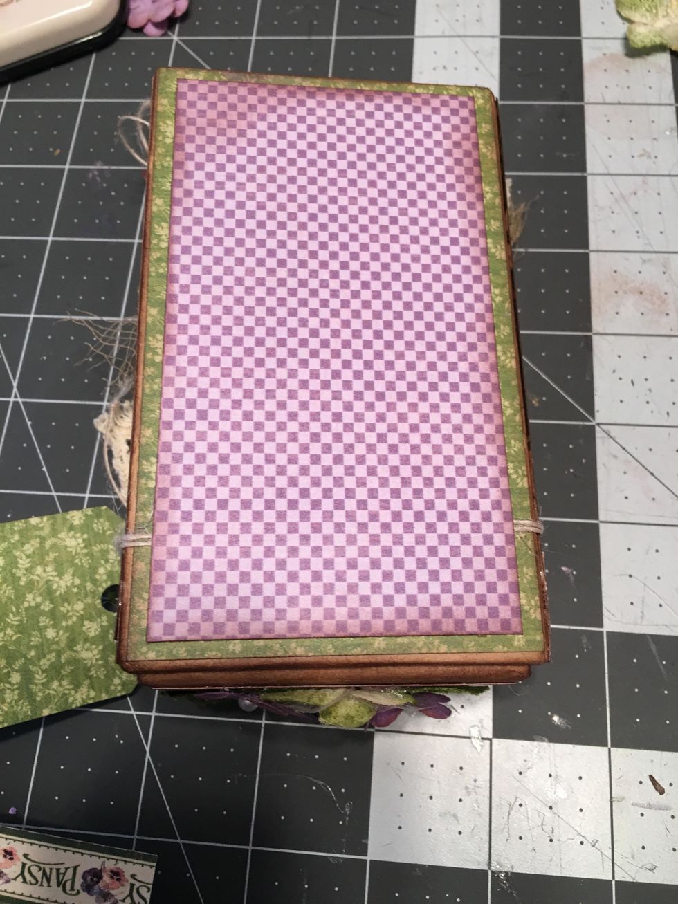 Measure and cut (ink the edges) of a piece of patterned paper and glue to the bottom side of the lid to securely hold the button string in place.