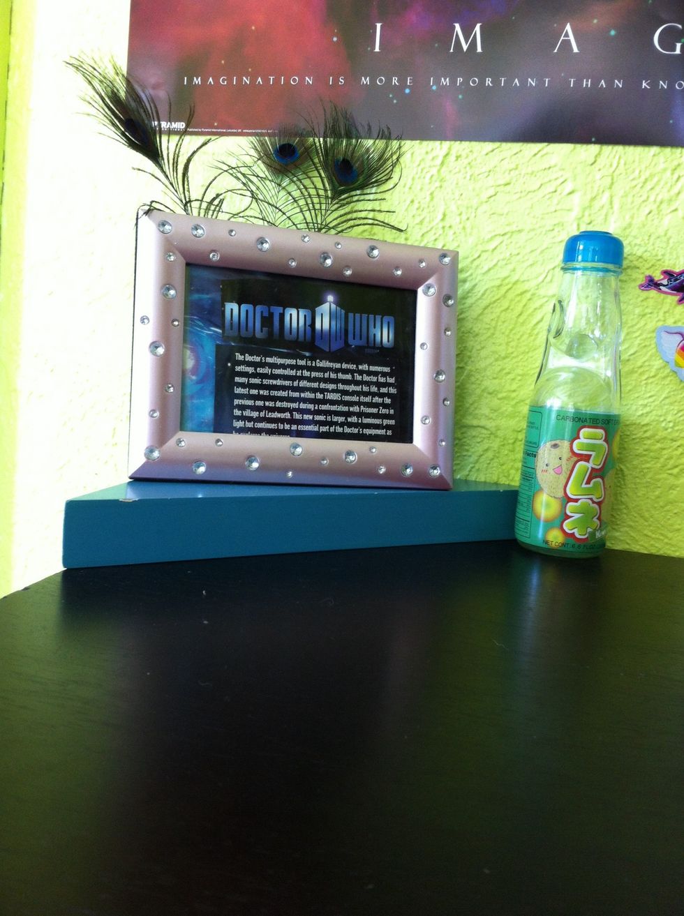 Might as well show you my desk while we're here. Here's my doctor who framey thing I made and some peacock feathers from a farm on a blue corner shelf. Next to it is my foreign kiwi soda bottle.