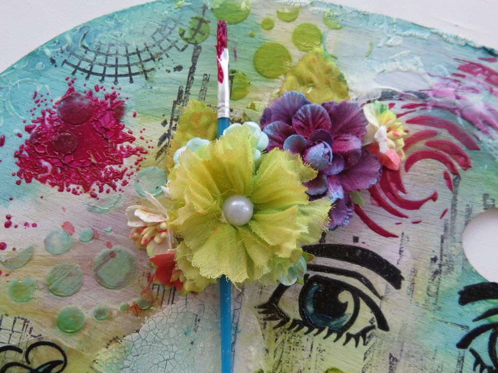 Mist some fabric and paper flowers with the sprays and paints from the previous steps. Arrange them over the forehead and add an used paint brush in the middle.