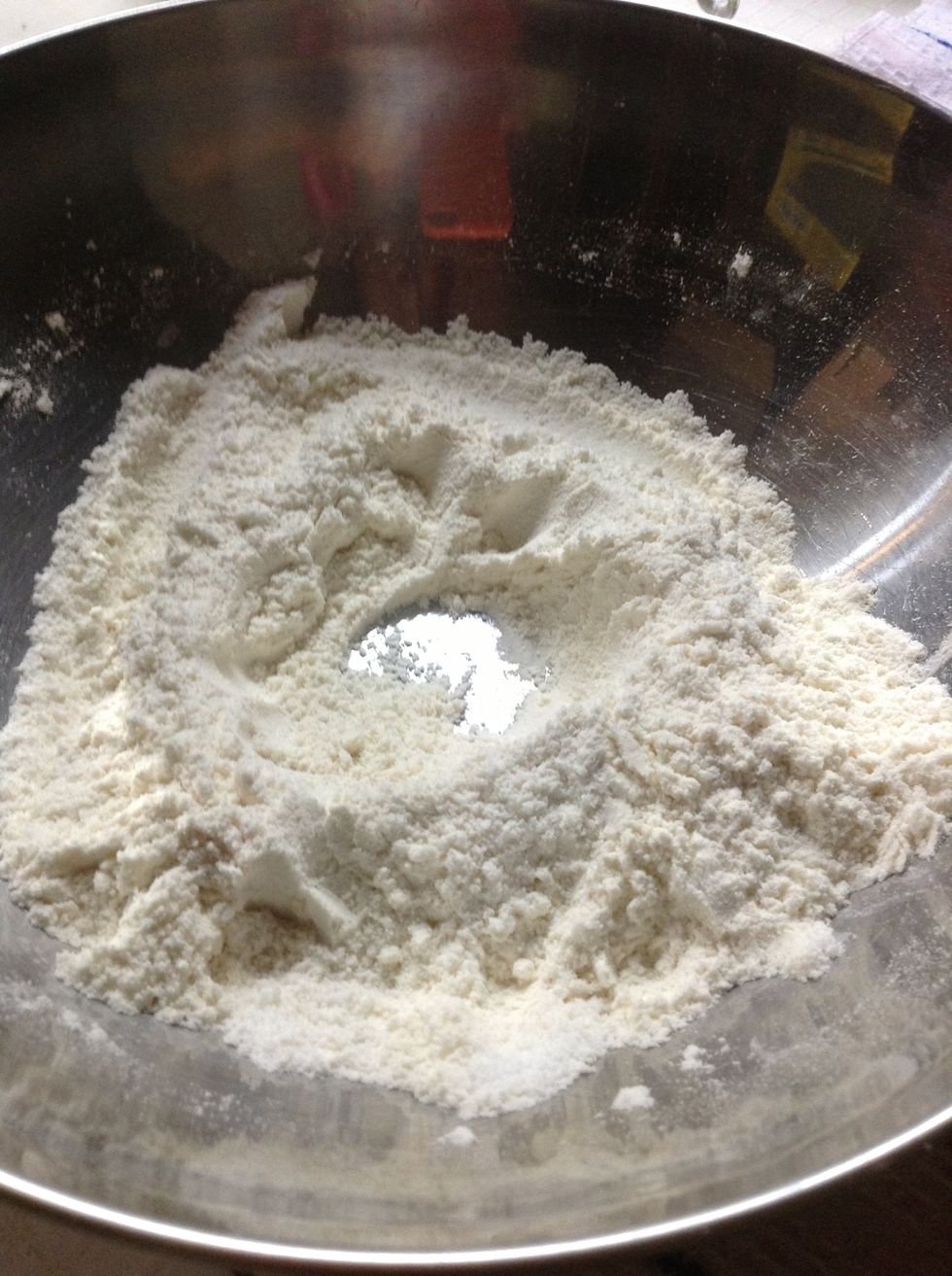 Mix the flour and the sugar together with a spoon or spatula. Then make a well in the middle of the mix.