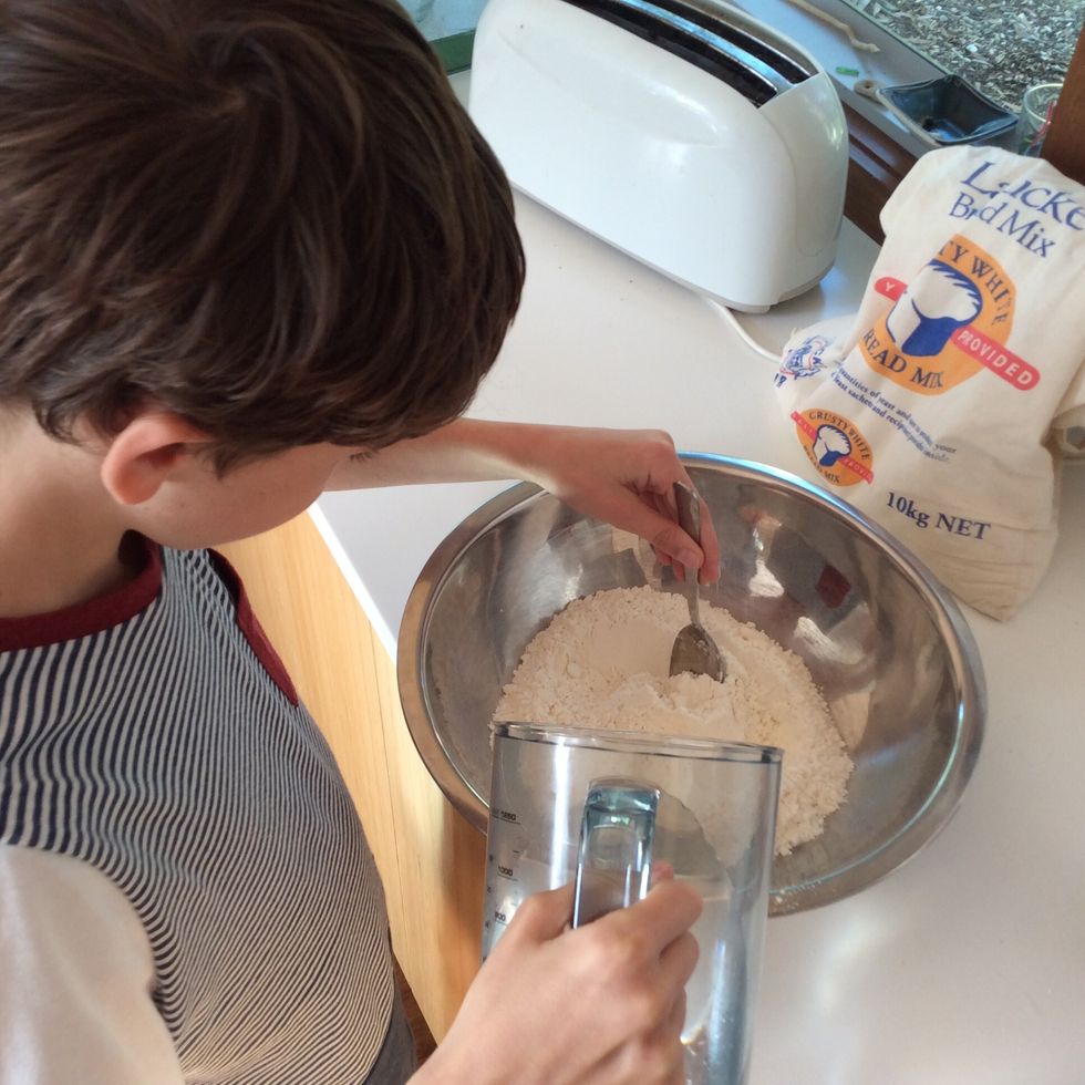 Mix the salt, yeast, and flour together and whilst doing so, add water. Once the mixture has become doughy then plop it onto your bench.