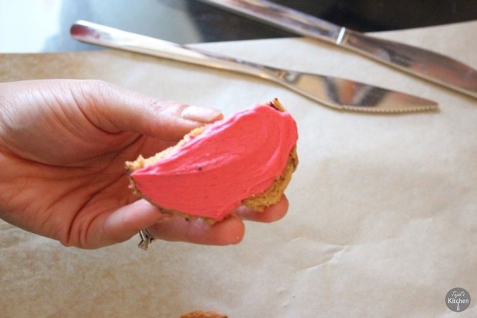 Mix together the 25g of butter soften, icing sugar, red food colouring and milk until a cream frosting. Spread the frosting over top  and bottom half of the cookie