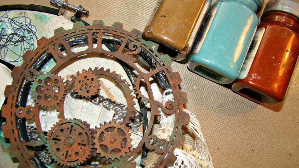 Mixing my 3 paints with some craft sand provides that grit that is nice for added a rust and patina'd effect. Add these to my clock face and cogs and gears. Glue to the top of the smallest hoop.