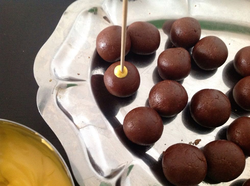 Mojamos la punta de la brocheta en chocolate y la pinchamos con cuidado y despacio para no agrietar la bola. Pinchamos todas y dejamos endurecer el chocolate.