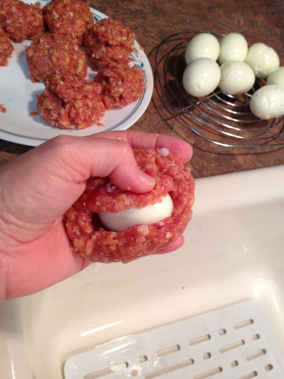 Mold meat totally around egg. I find it's easiest if your hand is first rinsed in warm water and still wet. Meat doesn't stick and is easier to mold.