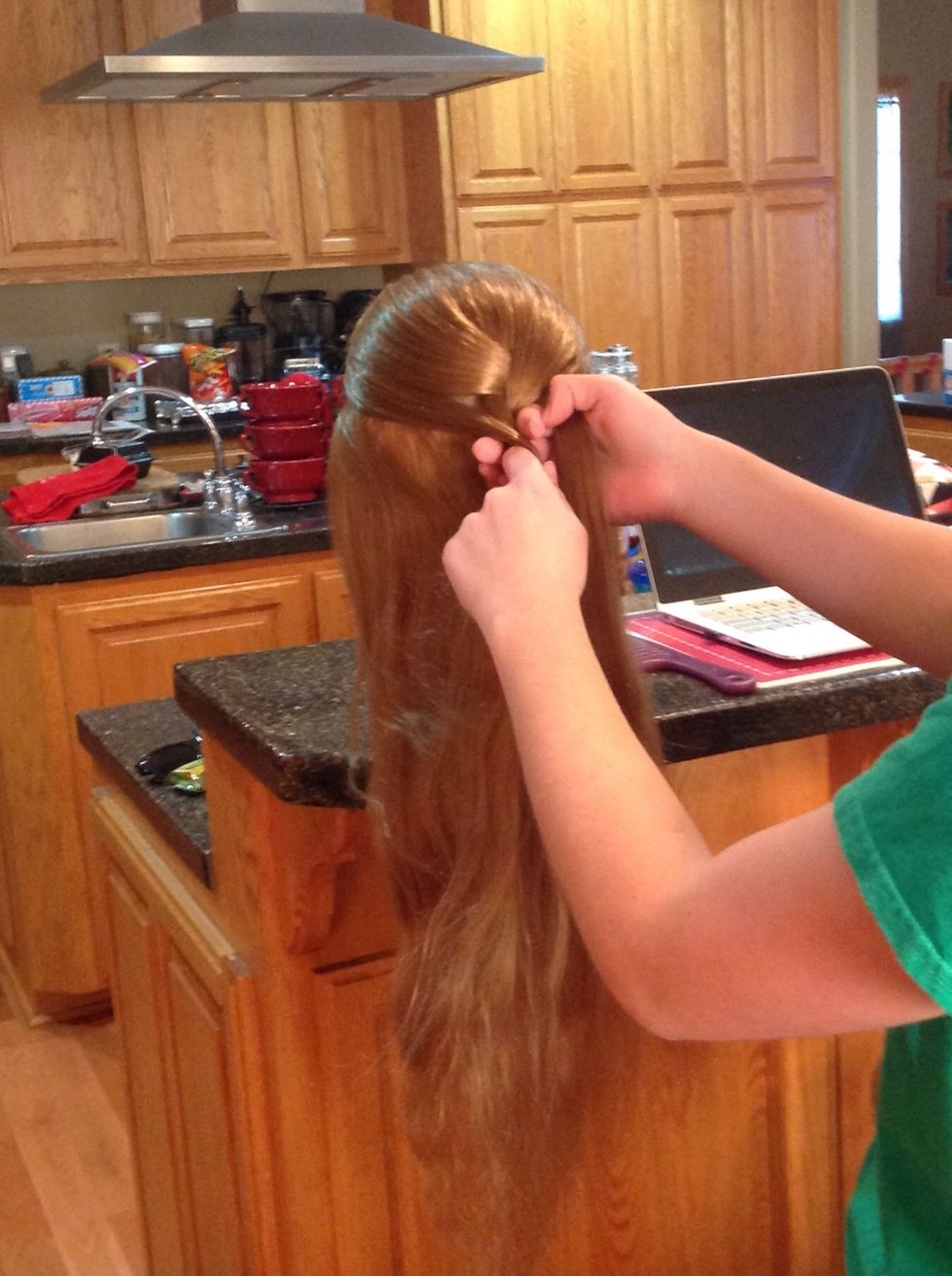 Move the opposite outside piece to the center, this time adding another small section of the hair from the hair that is down. Make sure to smooth out the newly added hair when you add it to the braid.