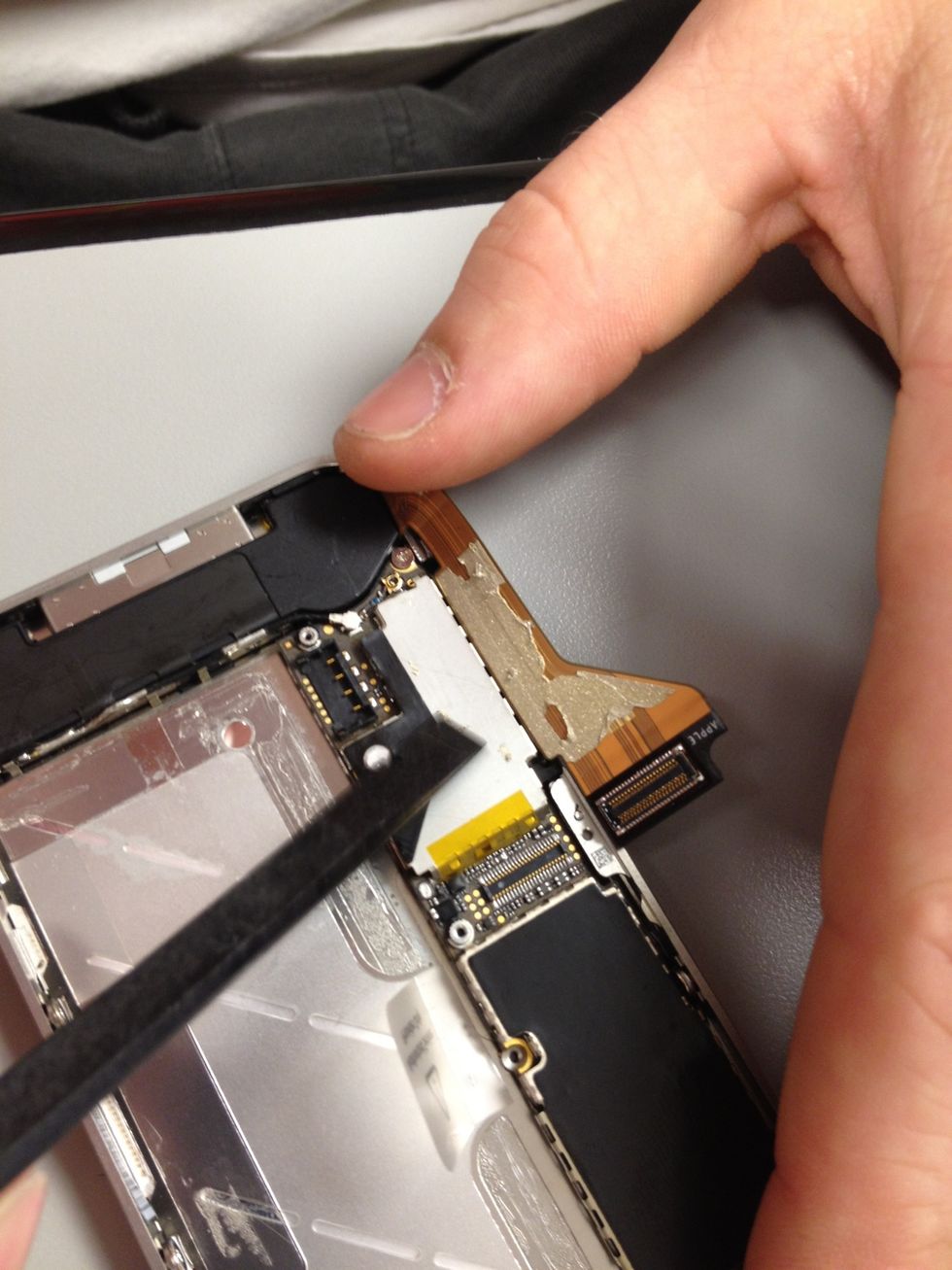 Moving to the bottom of the phone, peel back the dock ribbon cable. Fragile territory we are heading into now. Ribbons tear extremely easy.