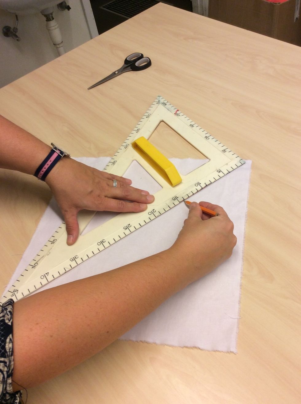 N\u00e4r du f\u00e5tt ditt undertyg till kudden ska du m\u00e4ta ut mitten. Ta en stor linjal och l\u00e4gg diagonalt \u00f6vertaget. Rita med tygpenna.