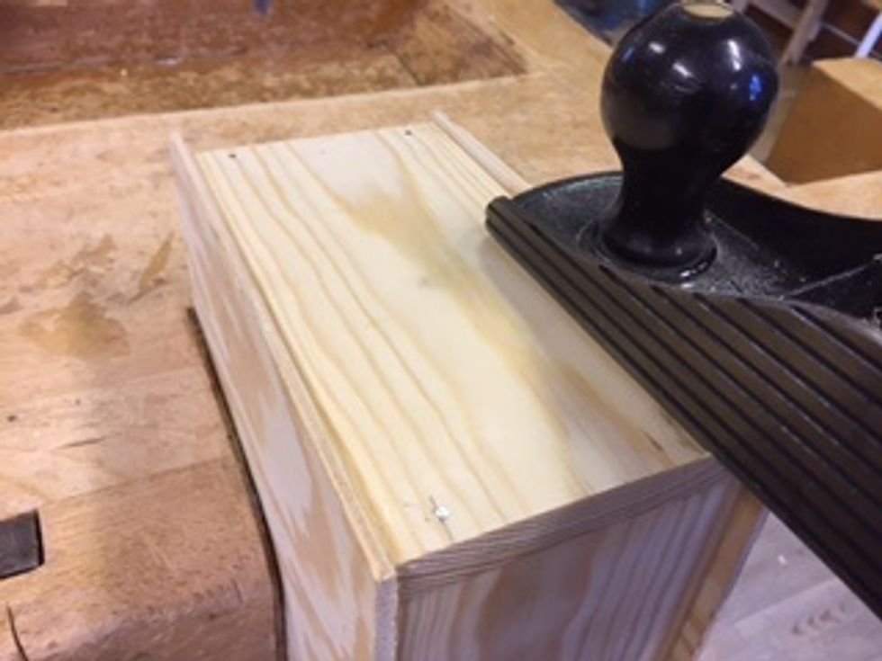 N\u00e4r limmet har torkat kan du hyvla l\u00e5ngsidorna. Sp\u00e4nn fast l\u00e5dan. Hyvla ned plywooden tills den n\u00e4stan \u00e4r j\u00e4mn med l\u00e5dan. Hyveln f\u00e5r inte ta i l\u00e5dan f\u00e5r d\u00e5 blir det m\u00e4rken. Vinkla hyveln lite ut\u00e5t.