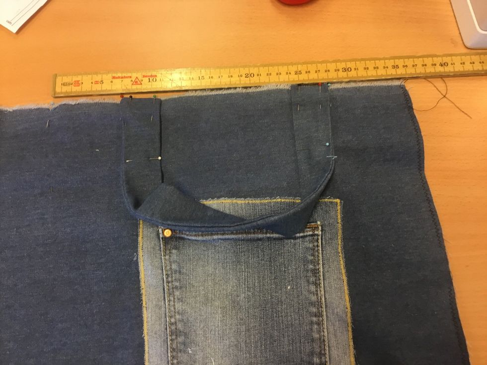 N\u00e5la fast handtagen som p\u00e5 bilden, 7 cm fr\u00e5n kanten. Sy fast handtagen 3 cm ner p\u00e5 kassen med raks\u00f6m. Gl\u00f6m inte f\u00e4sta.