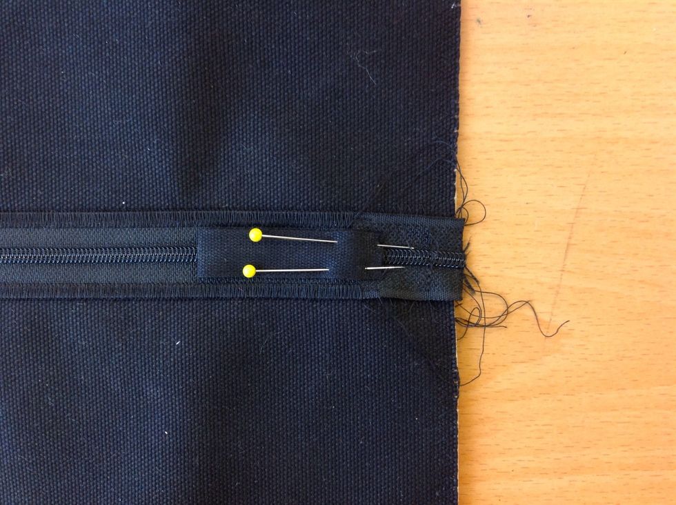 N\u00e5la fast ovanp\u00e5 dragkedjan p\u00e5 r\u00e4tsidan (ovansidan). De tv\u00e5 \u00f6ppna \u00e4ndarna ska peka ut\u00e5t.