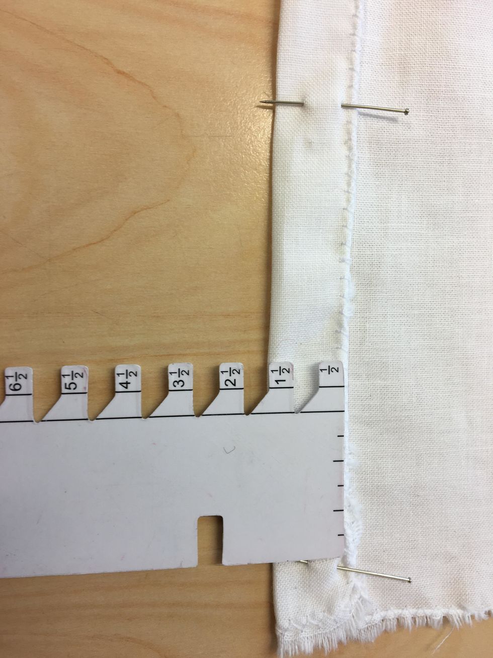 N\u00e5la in 1.5 cm p\u00e5 l\u00e5ngsidorna av tyget. S\u00e4tt n\u00e5larna p\u00e5 tv\u00e4ren s\u00e5h\u00e4r s\u00e5 kan du sedan sy \u00f6ver dem. Anv\u00e4nd denna lilla m\u00e4tstickan som ligger i din l\u00e5da.