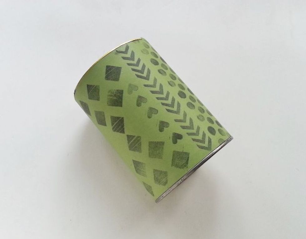 Neatly wrap the paper around the can and apply glue at the end to secure the wrapping.