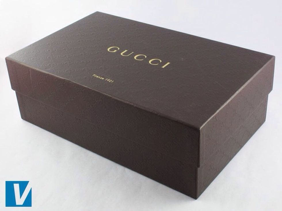 New Gucci heels packaged in a strong brown shoe box that features the double 'GG' logo embossed in a chain like pattern. The 'GUCCI' logo is across the middle.