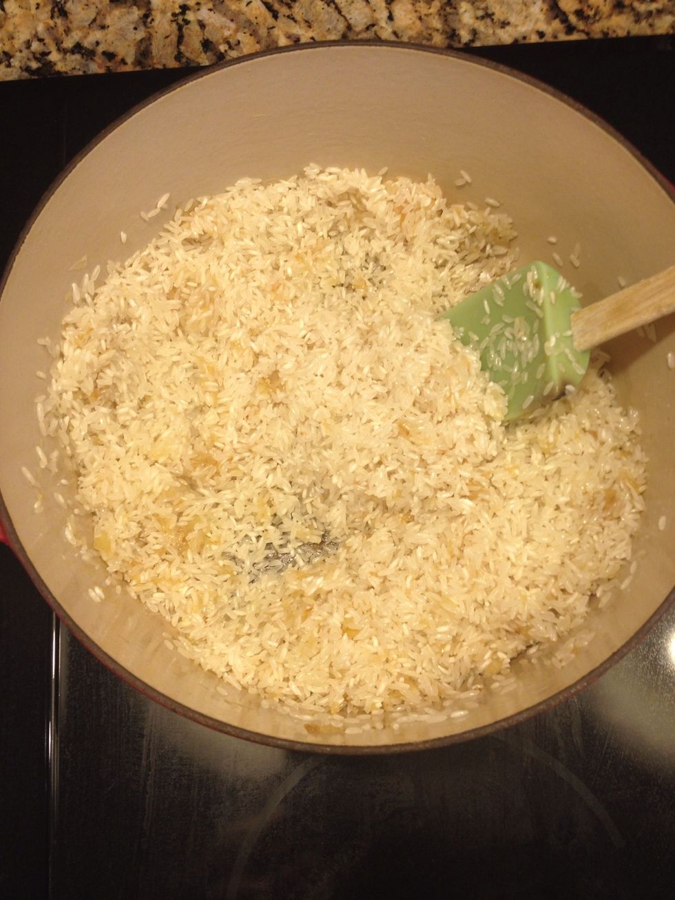 Next add 2 cups long grain white rice. Stir to warm and coat. Then remove from heat