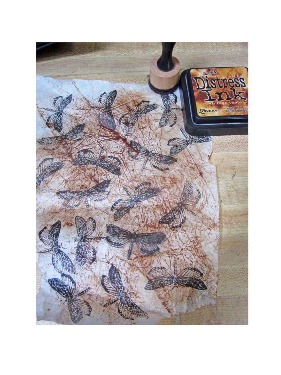 Next add distress ink to the top of the tissue paper. I'm using the Vintage Photo ink. Then spritz the paper with water to blend the colors more.
