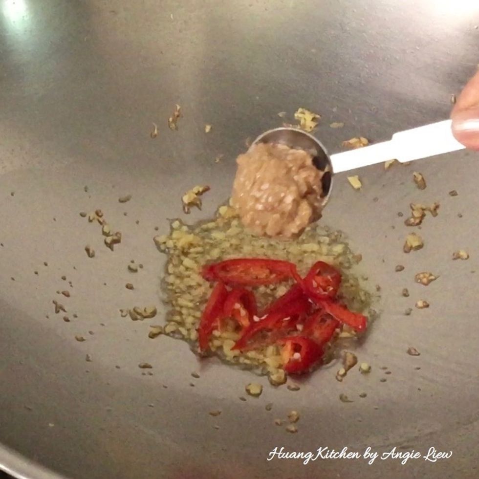 Next, add in the cut red chilies and mixed sauce. Stir fry until fragrant over high heat, about 1 minute.