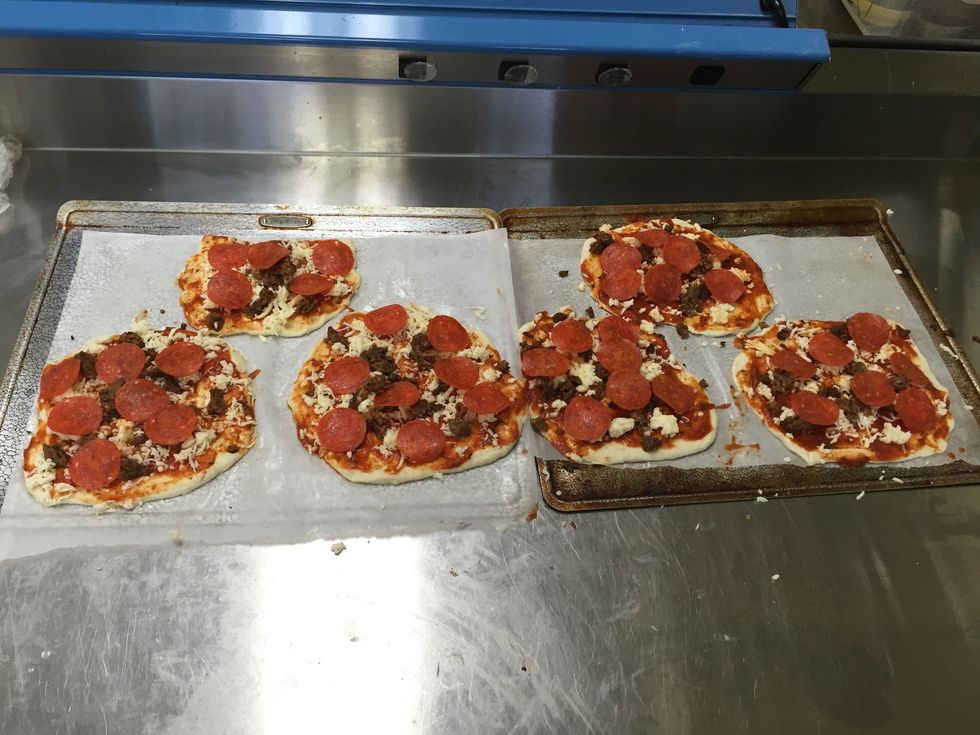 Next, add the 8 ounces of hot Italian sausage, 5 ounces of pepperoni, and 1 cup of cheese onto the circles.