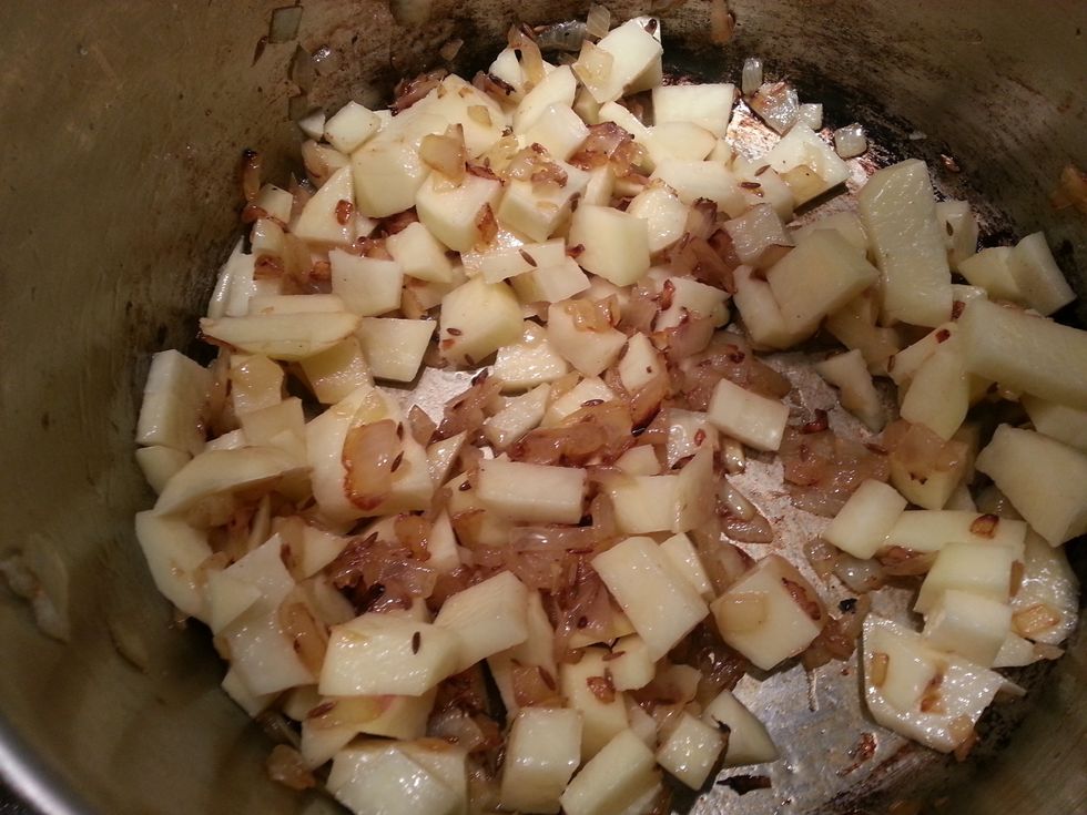 Next add the garlic, ginger, cumin and potatoes. Add a pinch of salt and allow to cook for 5 minutes.