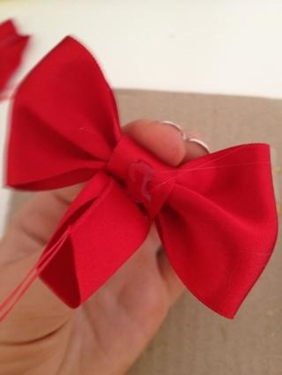 Next, because your ribbon may be a bit long, place a small amount of hot glue and then continue folding so it stays secure. Keep doing this until you finish with your ribbon.