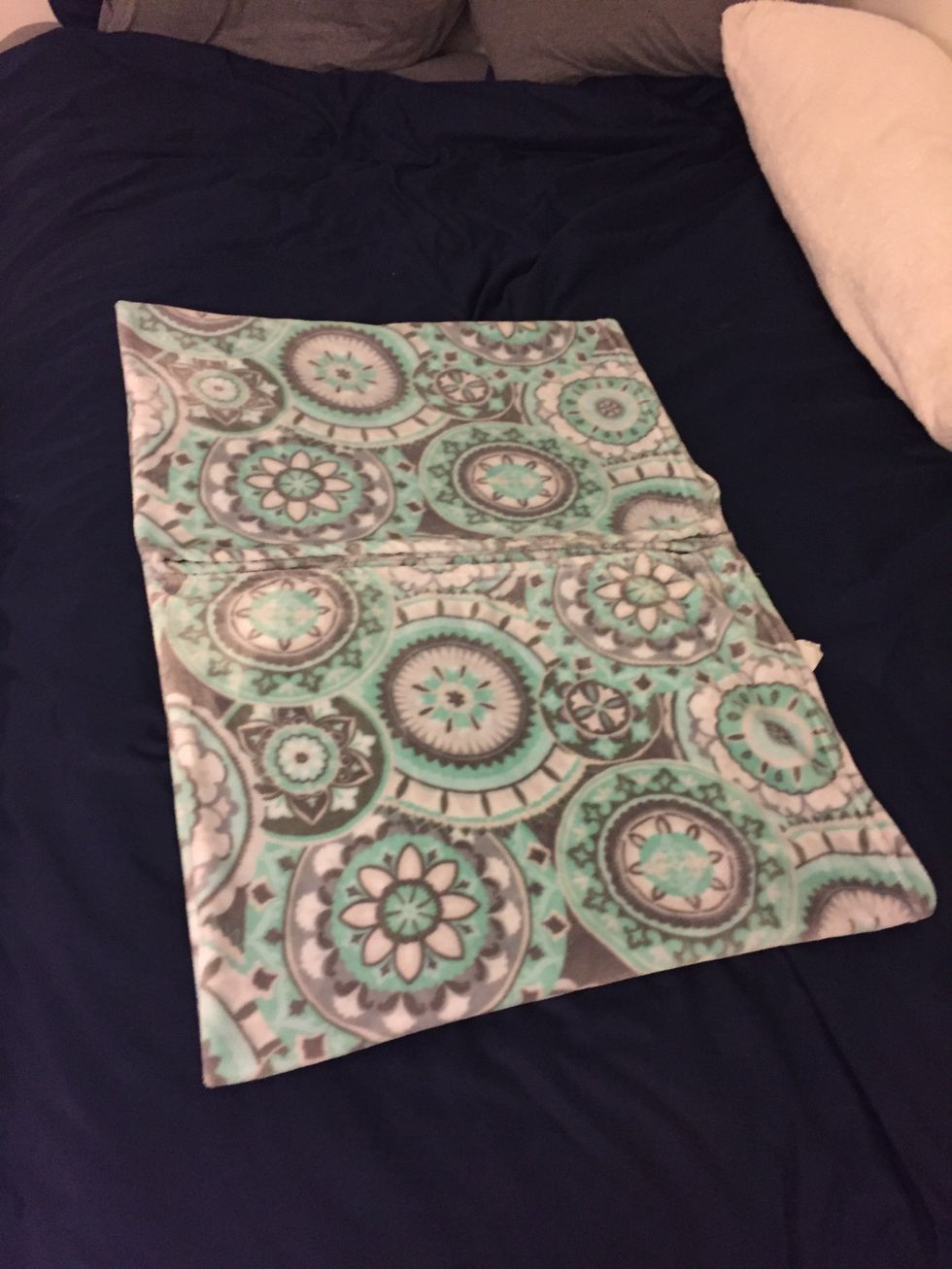 Next, Bring the opposite short edge to meet the middle of the blanket so it is facing the other side of the blanket. You can readjust where the middle is by looking at the two halves of the blanket.