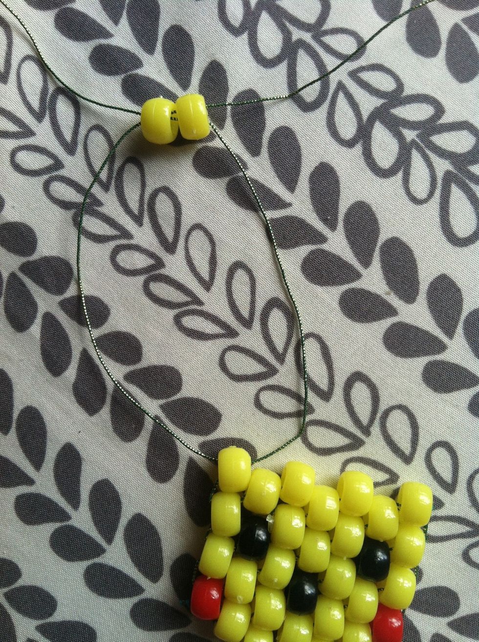 Next cut another piece of string and thread it halfway on the corner yellow bead and add 2 yellow beads on one string then thread the other string in a different direction through the bead.