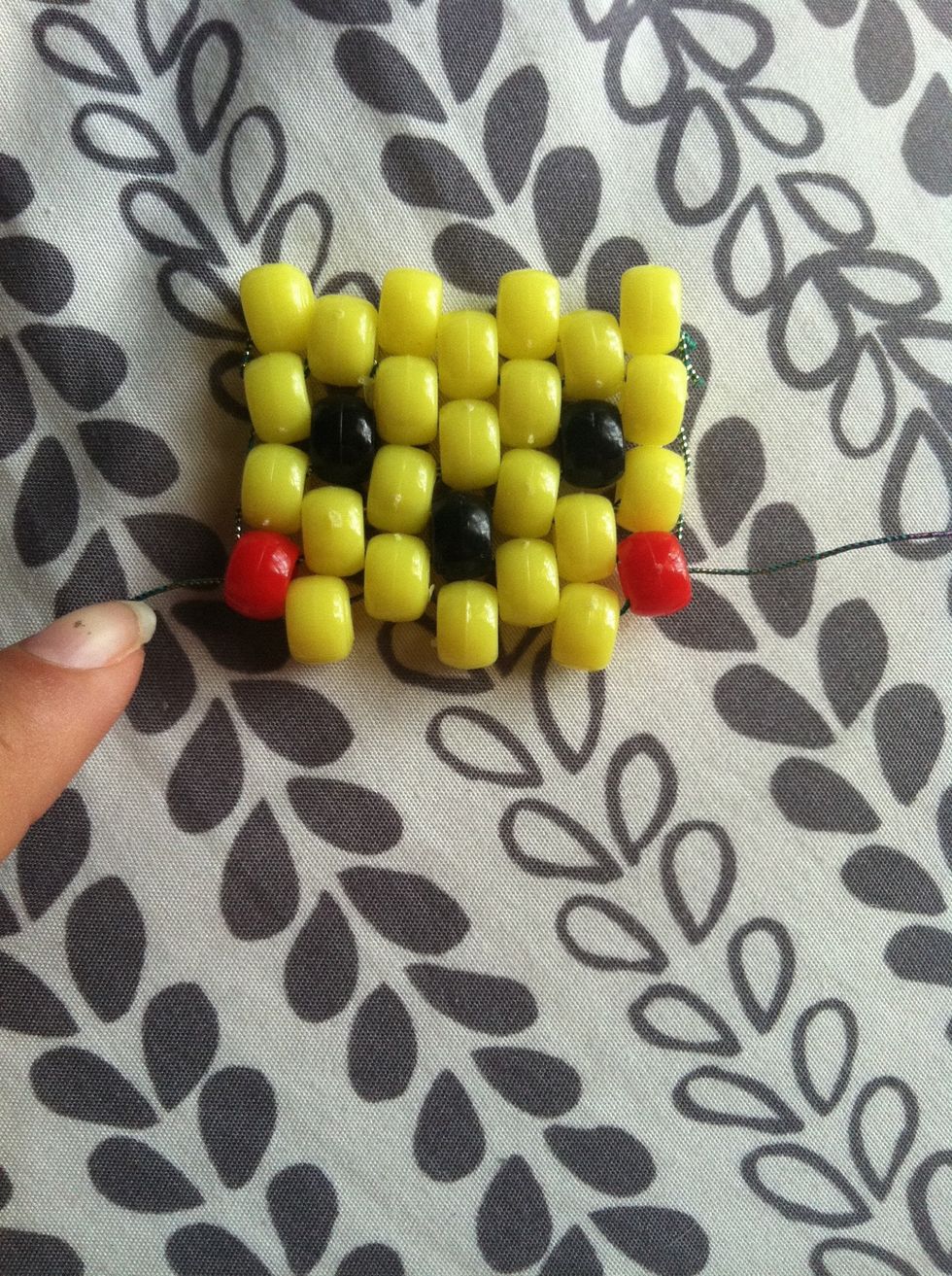 Next cut another piece of string and thread it through the red bead on the bottom halfway and add 3 more yellow beads.