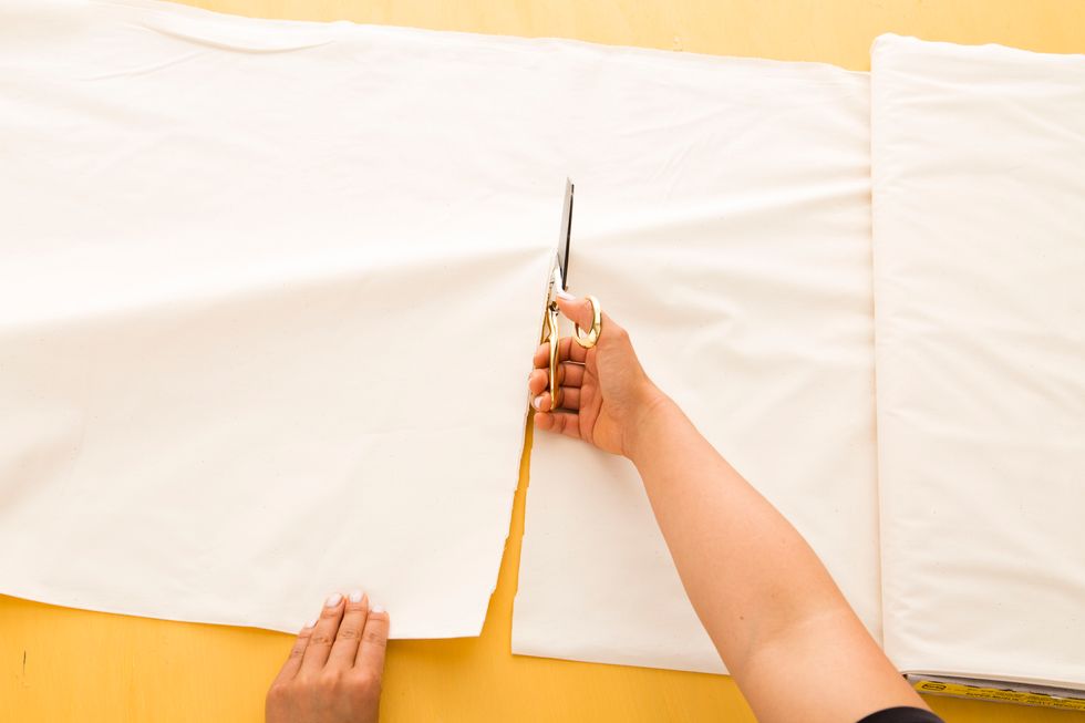 Next, cut two pieces of 10.5-foot-long white muslin fabric. Unfold each piece of fabric and lay them flat on top of each other.