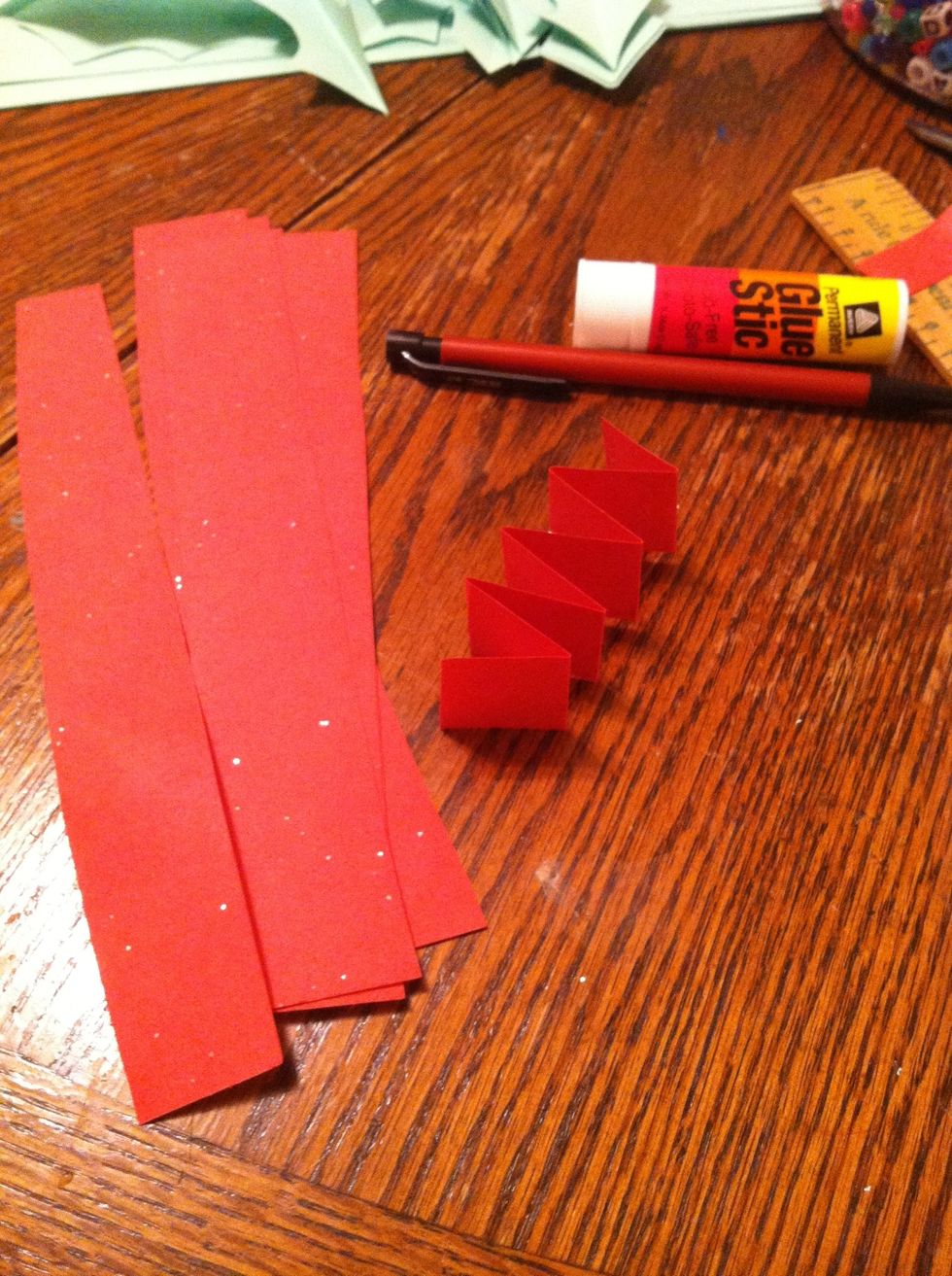 Next cut you red paper into strips. I just free handed it, there's really no need for perfection with this kind of project. Fold up your strips accordion style. Leave 3 strips on the side.