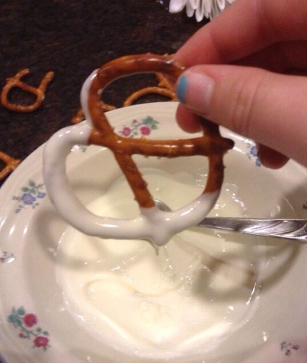 Next dip each pretzel about halfway into the melted chocolate. Let it drip for a few seconds