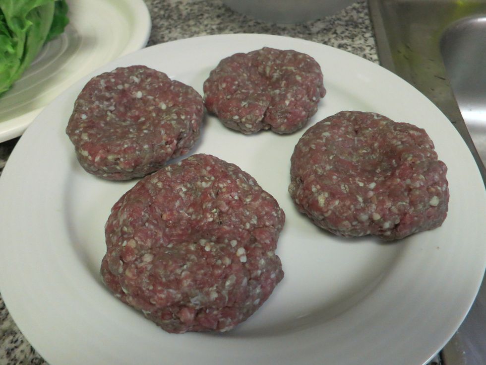 Next divide it into four equal round shape form. And then press the middle part so when we cook our patty it will not rise up.