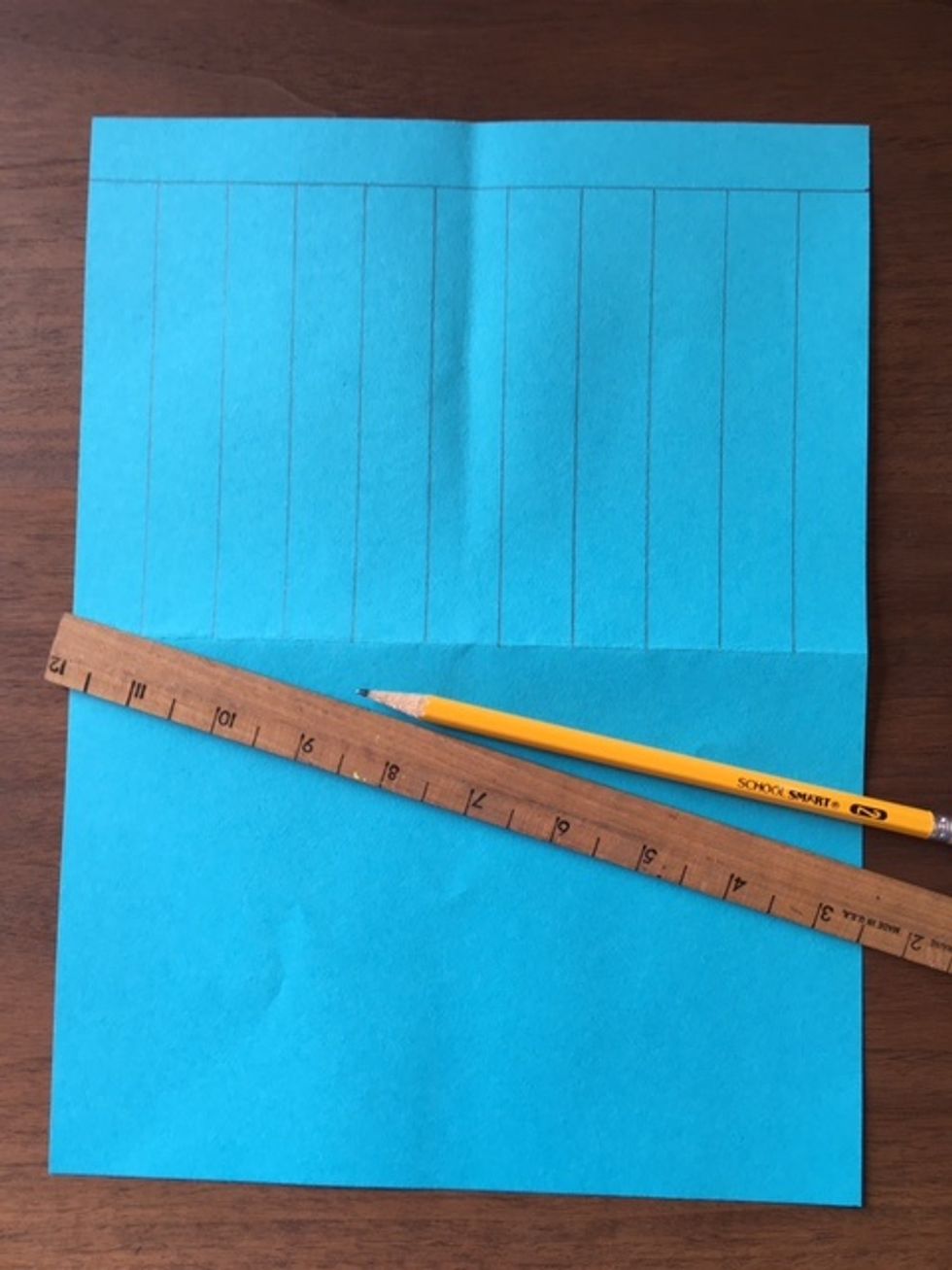 Next, draw pencil lines one inch apart using the width of the ruler as a guide. Draw lines with pencil across the paper. Draw lines from horizontal pencil line at top to crease line.