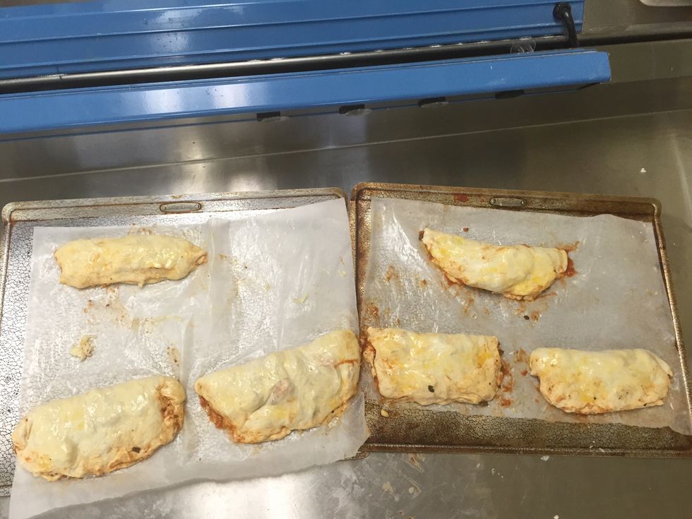 Next, fold the dough up, and pinch the sides in. Brush the top of the calzones with the egg.