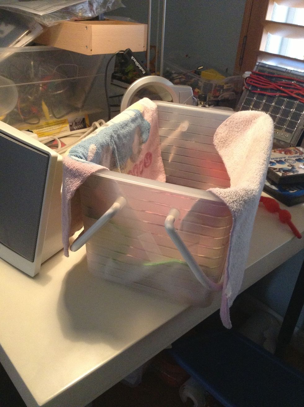 Next, get a container or box and tape or glue or drape towels or blankets over it