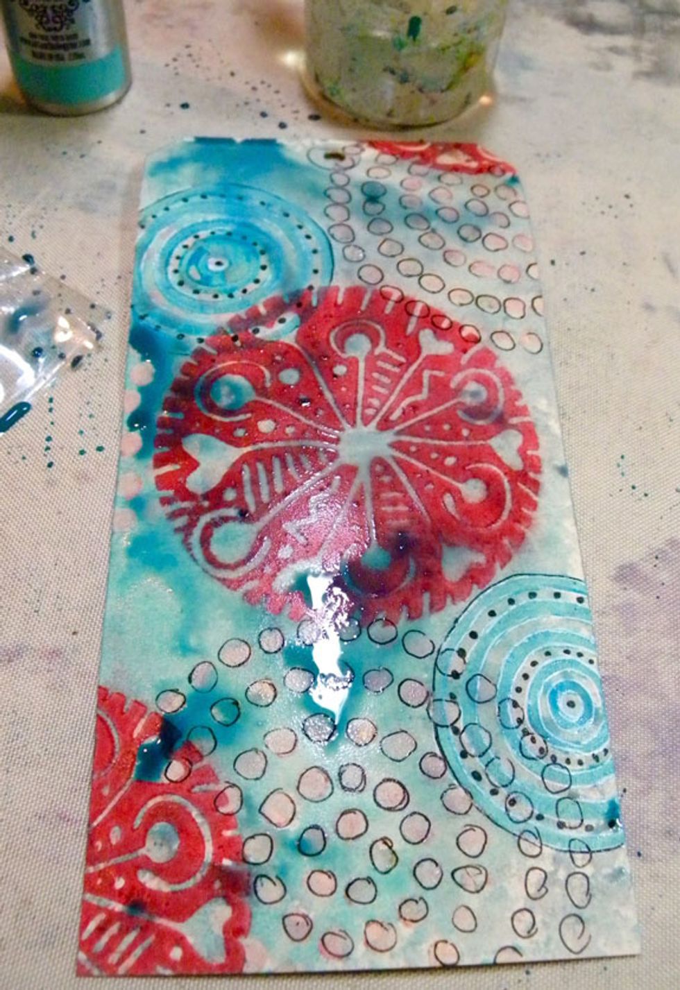 Next, I sprayed Waimea Bay and Siesta Key Colorations Sprays onto the circle tag and let it pool around the painted images. Use a heat tool to dry.