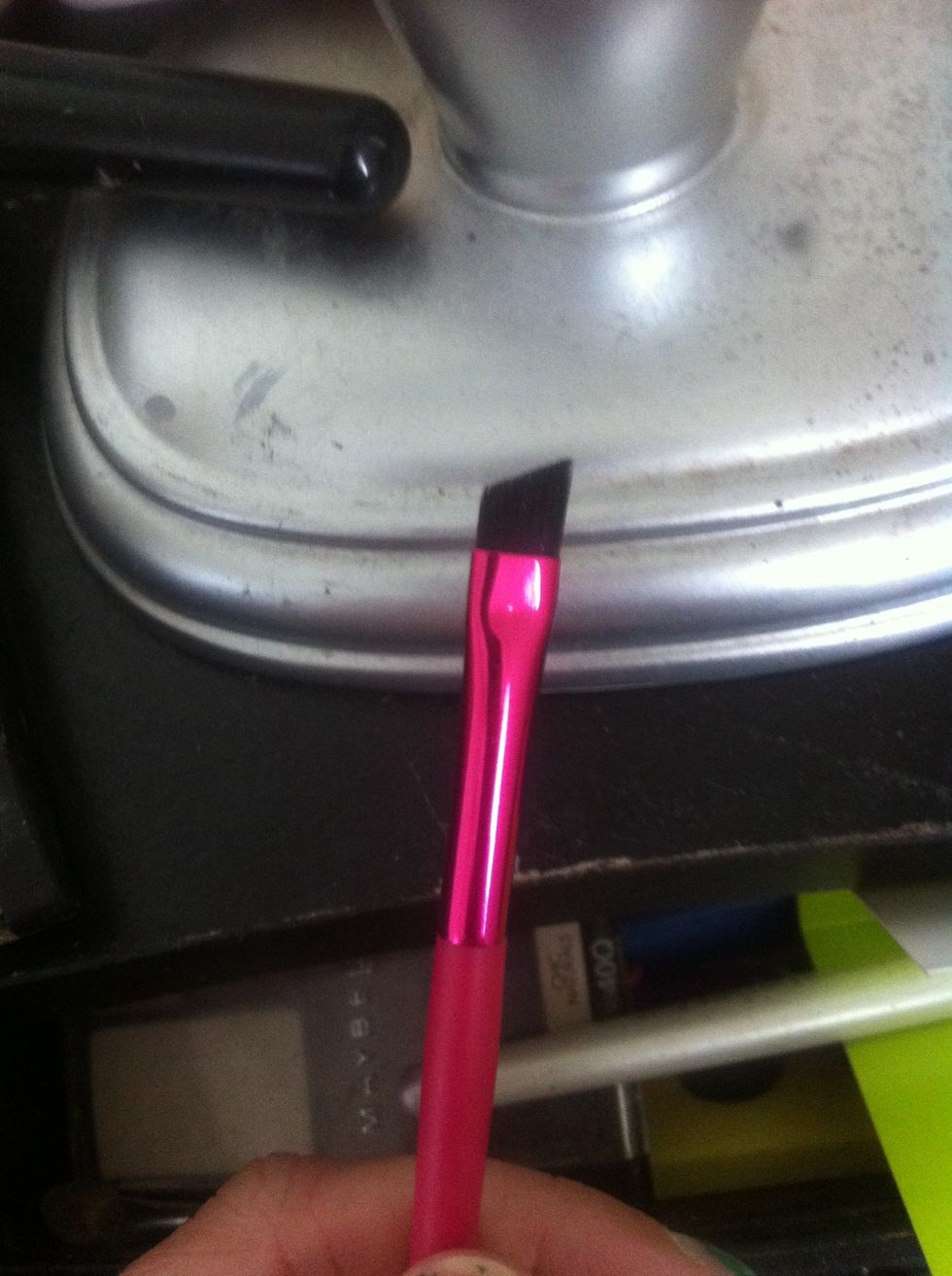 Next. I use an angled brush like this. To apply dark brown eyeshadow as an eyeliner. I used the bottom dark shimmery brown in step 1