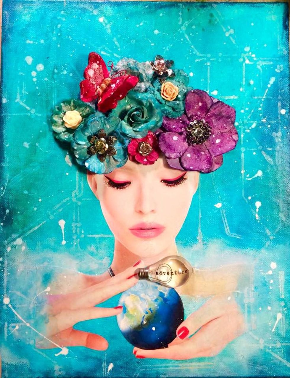 Next I used a stencil to create a mapped look on the background. I then covered her face, and using the white ink I splattered it on the entire canvas flowers and all. I added metal embelishments