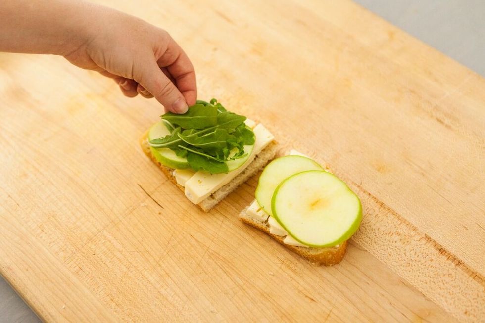 Next, layer several pieces of baby arugula.