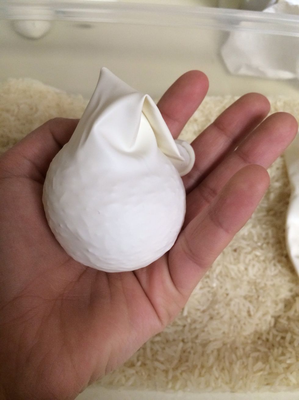 Next, mash all the rice down to the bottom of the balloon. It should almost look like a Christmas tree ornament.