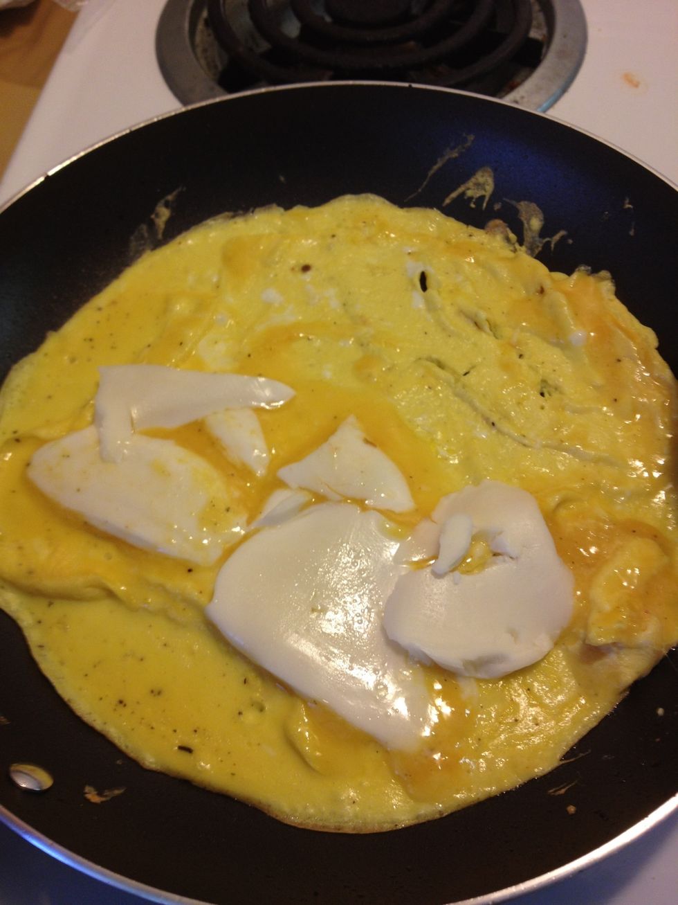 Next, place pan back onto stove and cook the whisked eggs. When the eggs are starting to form, add thin slices of mozzarella.