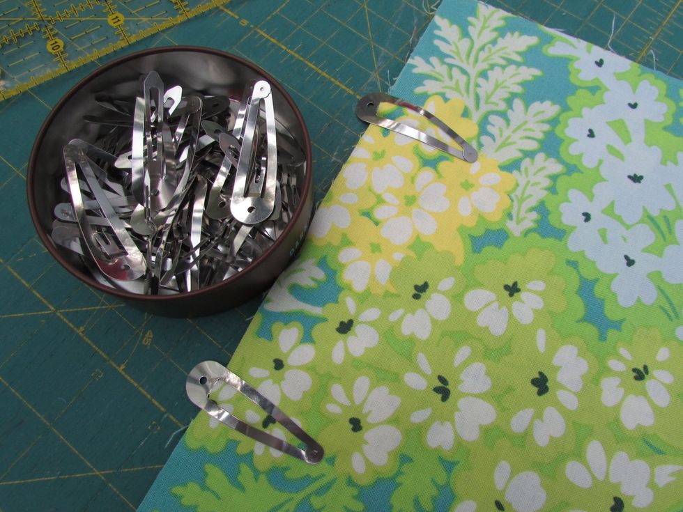 Next, place the now 11 x 7" folded pocket piece on one side of the quilted fabric. You can use pins to secure, but I like to use this dollar store spring hair clips instead (just don't sew over them!)