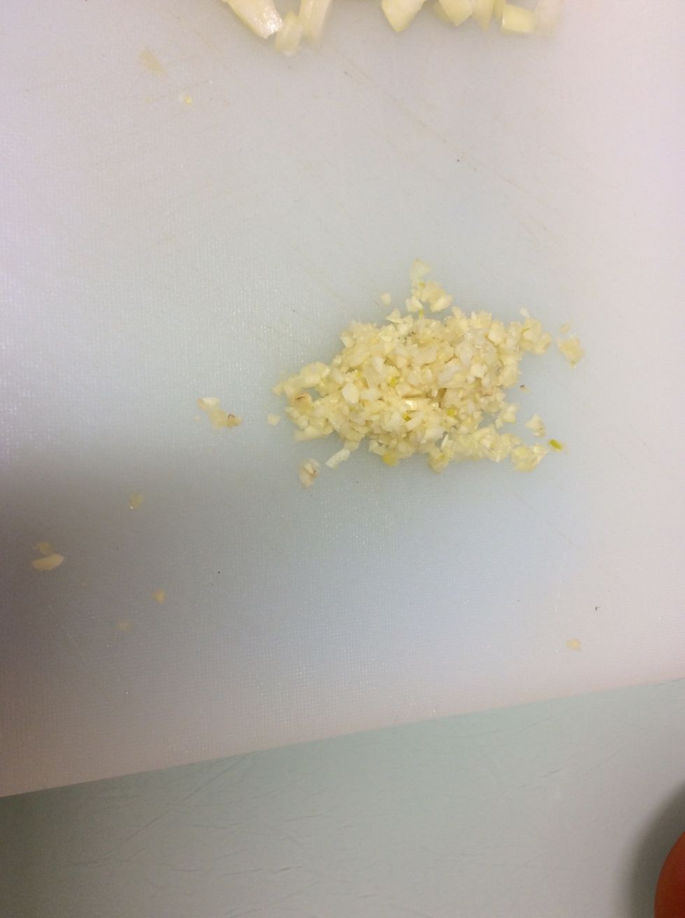 Next Press the garlic with the side of a knife. And finely dice it.