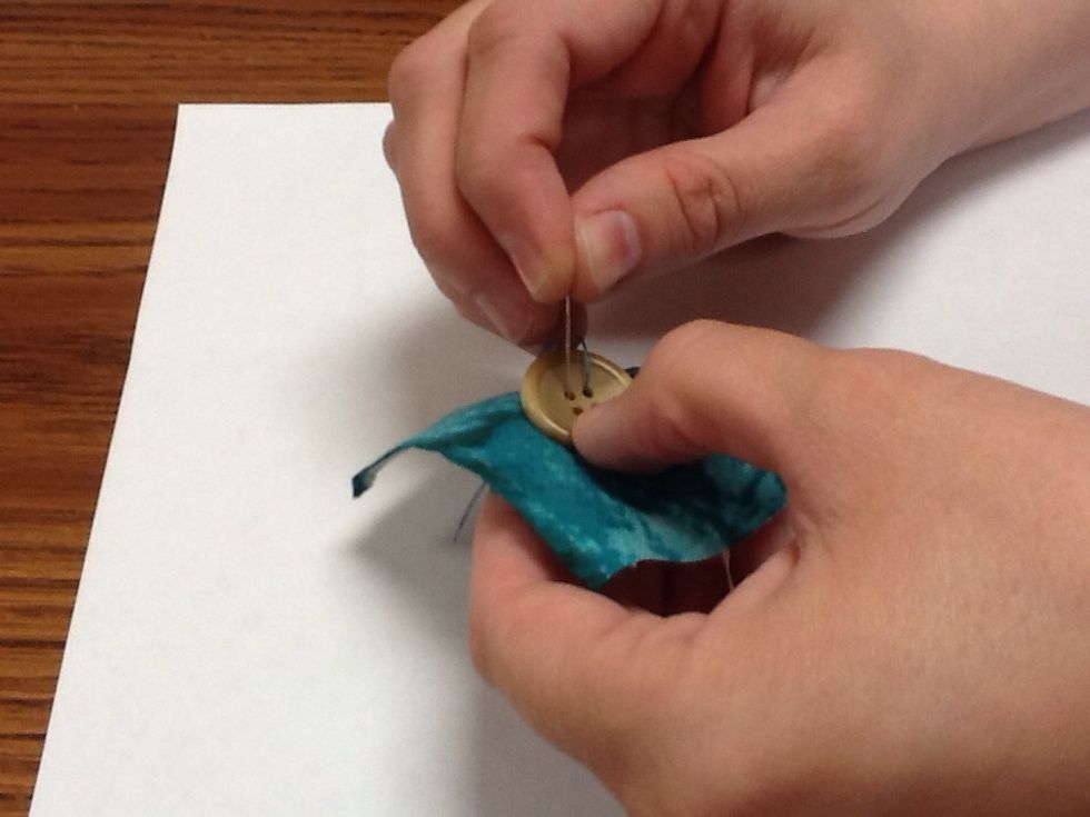 Next- push your needle through a different hole and back through your fabric. Pull tight.