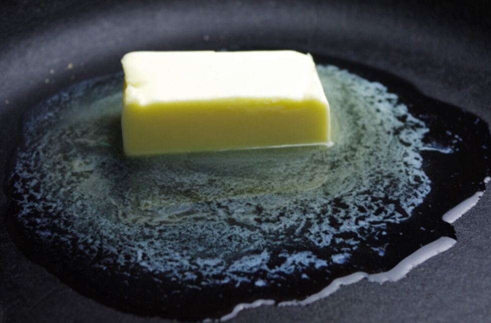 Next, put a small 'glob' of butter (or spray) into the pan. If using butter use a wooden spoon to spread the butter all over the pan.