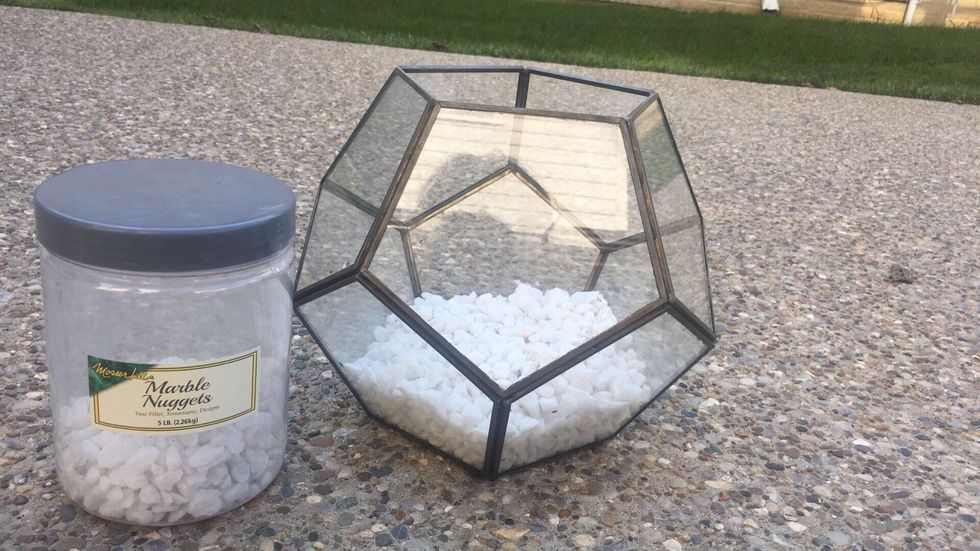 Next, put about 3/4 one of your containers of rocks into the bottom of your glass container or pot.