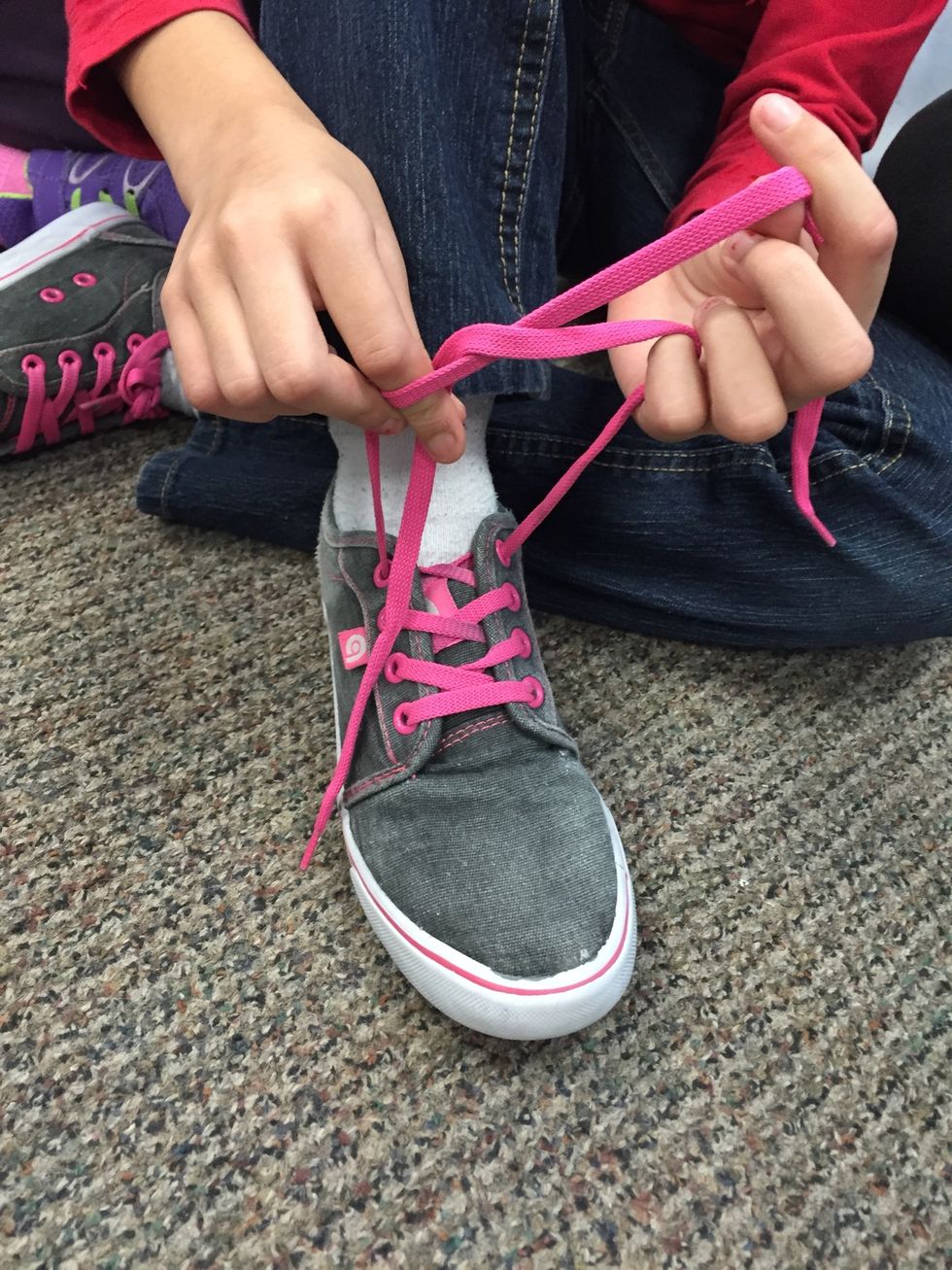 Next, Put one lace through the triangle made by the x to make a knot.