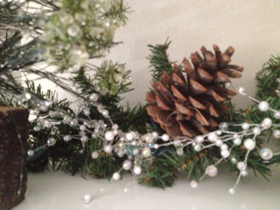 Next, scatter pine cones throughout the garland. I also use cinnamon sticks, twine balls, and leaves.