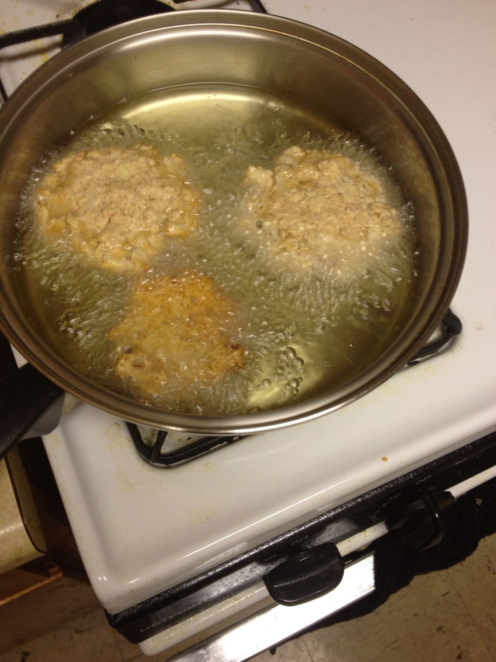Next, scoop out small balls of the salmon mixture and place in frying oil. Once the salmon balls are in the frying oil, flatten them into patties using a spatula. Cook for a few minutes on each side.