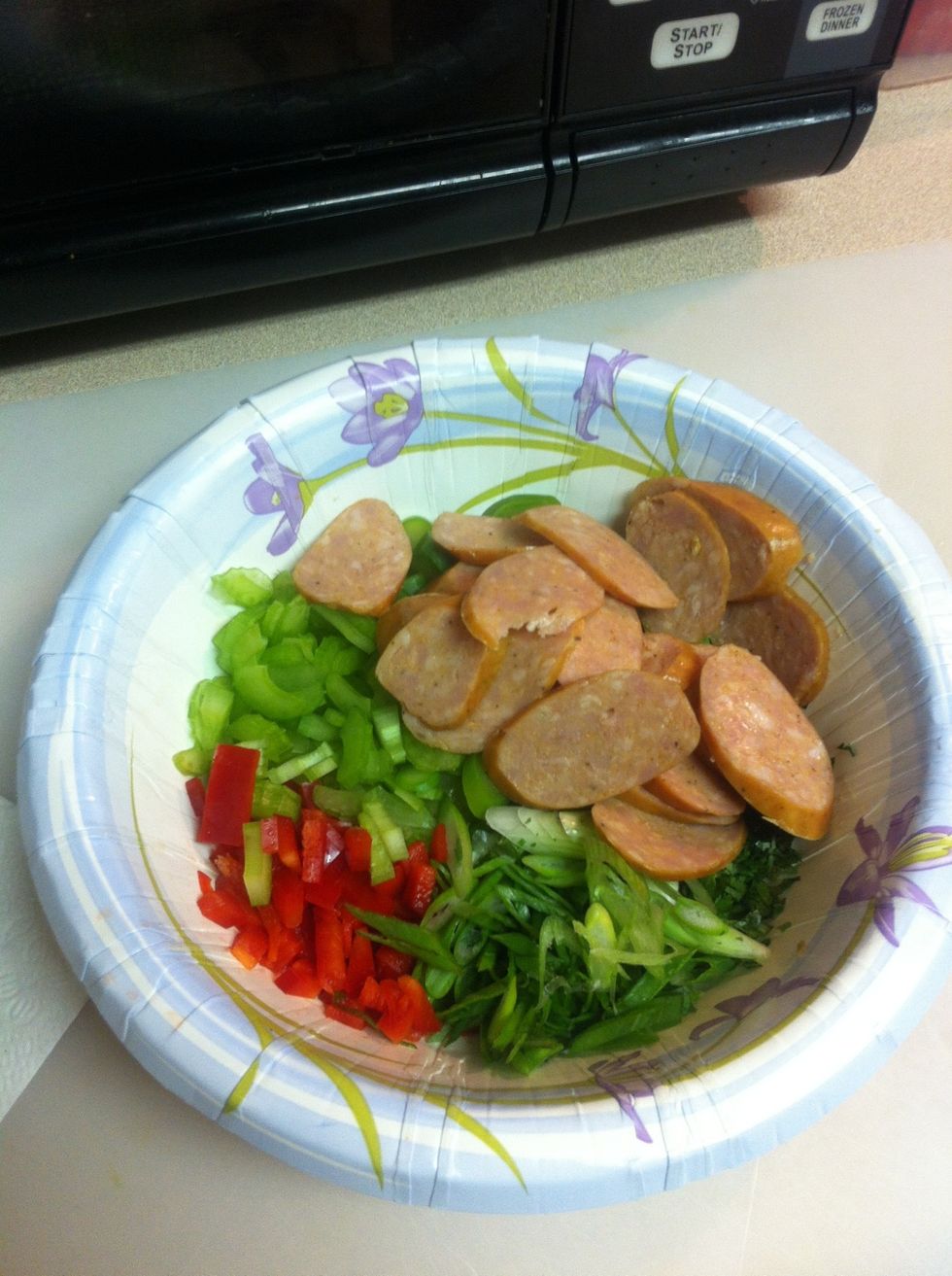 Next slice your green onions and asparagus and sausage then dice your red bell pepper and cilantro. Set them aside in a bowl.